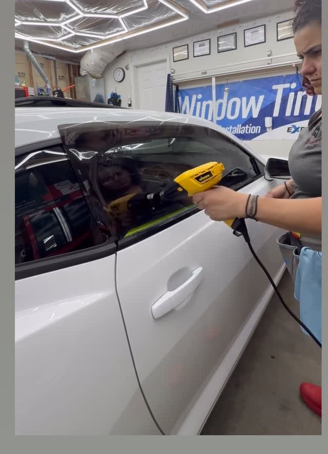 Rosie heat-shrinking window film on a white Chevy Camaro door glass