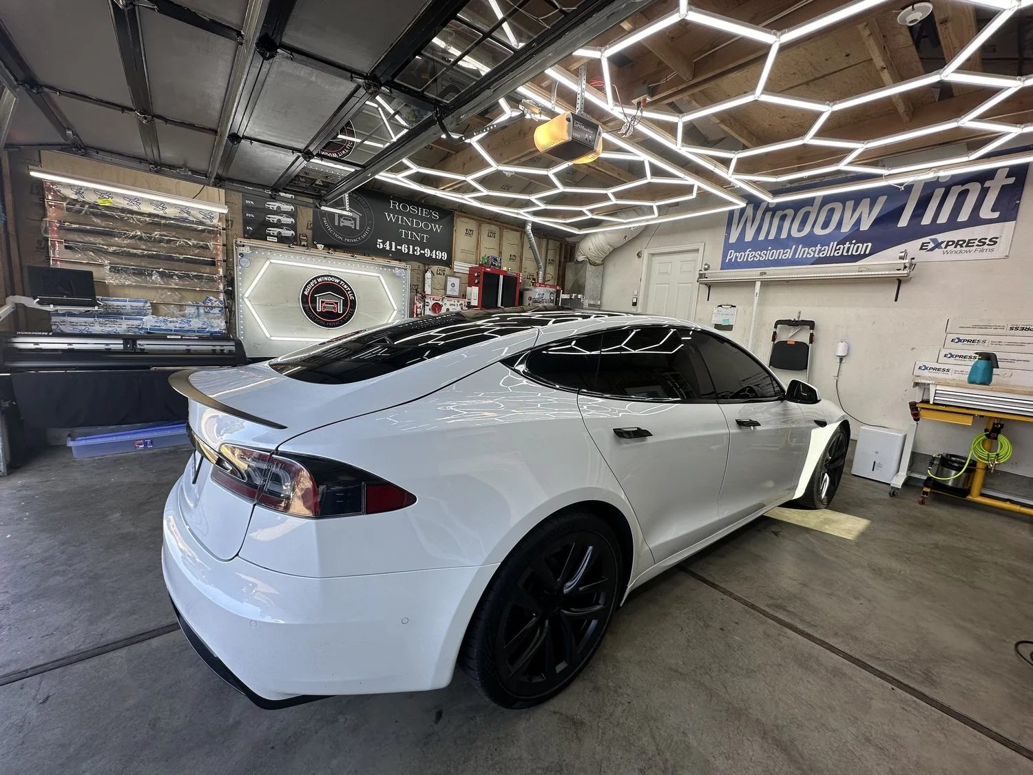 White Tesla with completed window tint under studio lighting at Rosie's Window Tint