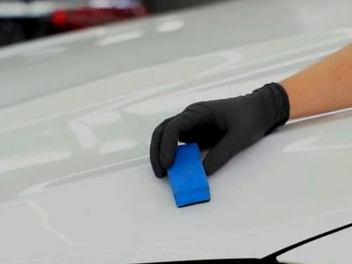 Installer applying paint protection film to a vehicle hood at Rosie's Window Tint